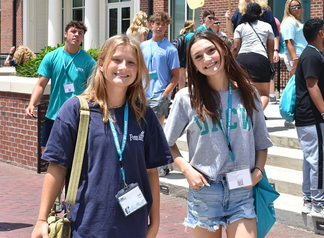 Two UNCW students smiling with their Orientation lanyards.